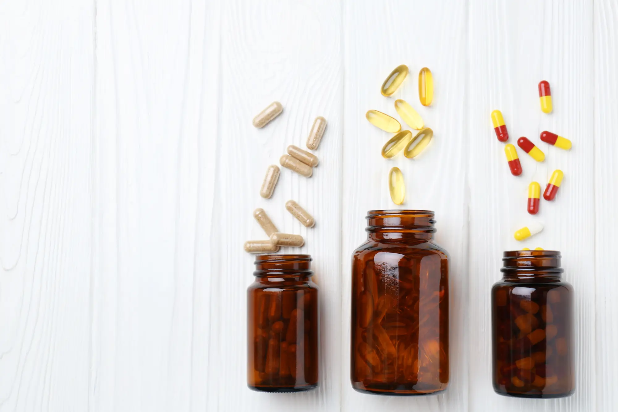 Staklene bočice sa različitim vitaminima i suplementima na beloj podlozi. Staklene bočice sa različitim vitaminima i suplementima na beloj podlozi.